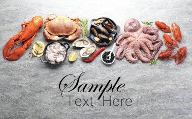 Gri masada farklı deniz ürünleri var, düz yerde. Metin için alanı olan tasarım
