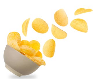 Lezzetli patates cipsleri beyaz arka planda kaseye düşüyor.