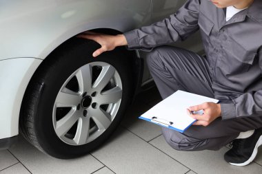 Tamirci araba servisinde değişiklik yaptıktan sonra lastikleri kontrol ediyor.