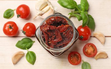 Lezzetli güneşte kurutulmuş domatesler, taze sebzeler, fesleğen ve sarımsak beyaz ahşap masa, düz uzanmış