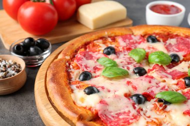 Gri masada lezzetli pizza ve malzemeler, yakın plan.