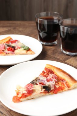 Ahşap masada servis edilen ince füme sosisli, lezzetli pizza dilimleri.