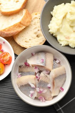 Siyah ahşap masada servis edilen soğanlı lezzetli ringa balıkları.