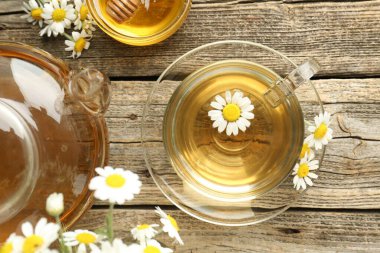 Cam bardakta nefis papatya çayı, taze çiçekler, bal ve çaydanlık ahşap masada, düz uzanmış