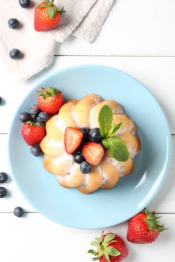 Beyaz ahşap masada pudra şekeri ve böğürtlenli Lezzetli kek.