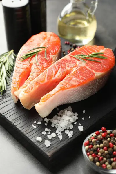 Deniz ürünleri. Çiğ somon bifteği, biberiye ve baharatlar gri masada, yakın plan.