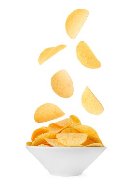 Lezzetli patates cipsleri beyaz arka planda kaseye düşüyor.