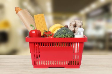 Süpermarketteki ahşap masada alışveriş sepeti dolusu kırmızı alışveriş.