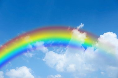 Mavi gökyüzünde parlak gökkuşağı güneşli bir günde bulutlarla