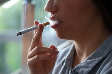 İçeride sigara içen bir kadın, yakın plan. Kötü alışkanlık.