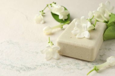 Bir kalıp sabun ve yasemin çiçekleri ışık masasında, yakın plan. Metin için boşluk