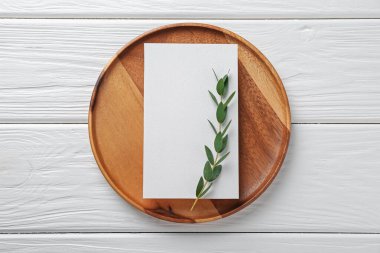 Boş davetiye kartı, tepsi ve dal beyaz ahşap masa, üst görünüm