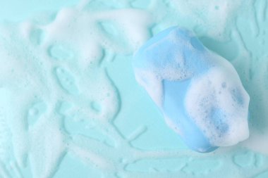 Açık mavi arka planda köpüklü sabun çubuğu, üst manzara. Metin için boşluk