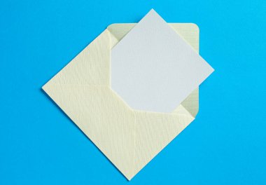 Açık mavi arka planda boş davetiye ve zarf, üst manzara. Tasarım için boşluk