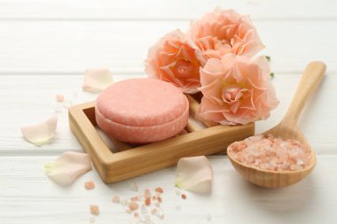 Sabun çubuğu, deniz tuzu ve beyaz ahşap masada güzel çiçekler, yakın plan.