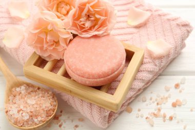 Sabun çubuğu, deniz tuzu ve beyaz ahşap masada güzel çiçekler, yakın plan.