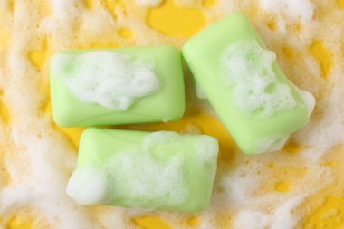 Sarı arka planda köpüklü sabun çubukları, düz yatış