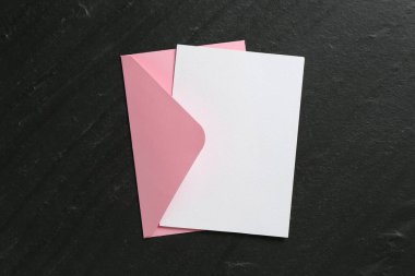 Boş davetiye kartı ve zarf siyah masanın üstünde, en üstte. Tasarım için boşluk