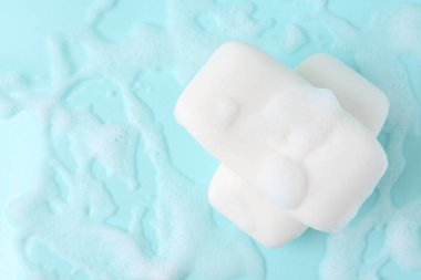 Açık mavi arka planda köpüklü sabun çubukları, üst manzara. Metin için boşluk