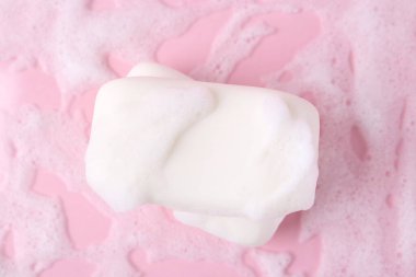 Pembe arka planda köpüklü sabun çubukları, üst görünüm