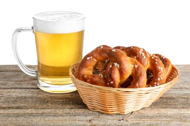 Lezzetli krakerler ve beyaz arka plana karşı ahşap masada bir bardak bira.