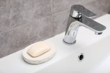 Musluğun yanındaki sabun barı banyoda lavabonun üstünde, yakın plan.