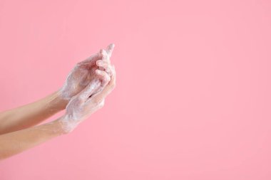 Açık pembe arka planda ellerini sabunla yıkayan kadın, yakın plan. Metin için boşluk