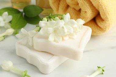 Sabun kalıpları, yasemin çiçekleri ve beyaz mermer masada havlu, yakın plan.