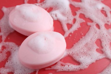 Kırmızı arka planda köpük olan sabun çubukları, yakın plan. Metin için boşluk