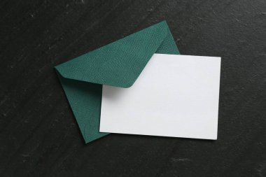 Boş davetiye kartı ve zarf siyah masanın üstünde, en üstte. Tasarım için boşluk