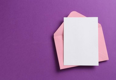 Mor arka planda boş davetiye ve zarf, üst manzara. Tasarım için boşluk