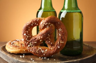 Lezzetli krakerler ve bira şişeleri ahşap masa üzerinde bej renkli gradyan arka plan, yakın çekim