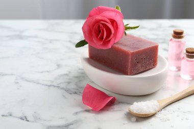 Sabun barları, kozmetik ürünleri ve beyaz mermer masada güzel bir gül. Yakın plan. Metin için boşluk