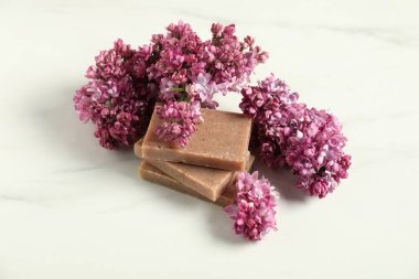 Beyaz mermer masada sabun ve leylak çiçekleri yığını