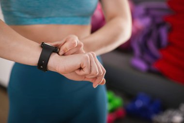 Kadın spor salonunda spor yaparken takip cihazını kontrol ediyor, yakın plan. Metin için boşluk