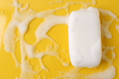 Sarı arka planda köpüklü sabun çubuğu, üst manzara. Metin için boşluk