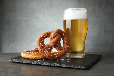 Lezzetli krakerler ve koyu dokulu masada bir bardak bira. Gri arka planda, yakın planda.