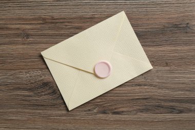 Ahşap masa üzerinde balmumu mühürü olan güzel bir davetiye zarfı.
