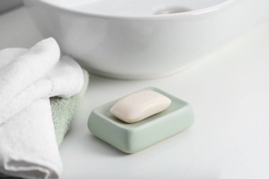 İçerideki beyaz tezgahta sabun çubuğu ve havlular, yakın plan.