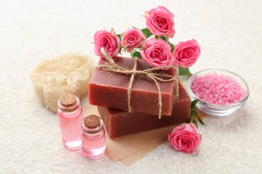 Sabun çubukları, deniz tuzu, temel yağlar ve bej masadaki güzel güller, yakın plan.