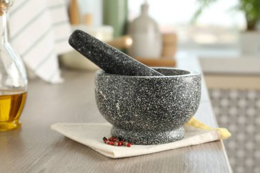 Mutfaktaki ahşap masada taş harç, tokmak ve baharatlar.