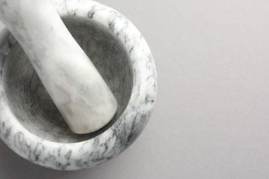 Açık gri zemin üzerinde mermer harç ve tokmak, üst manzara. Metin için boşluk