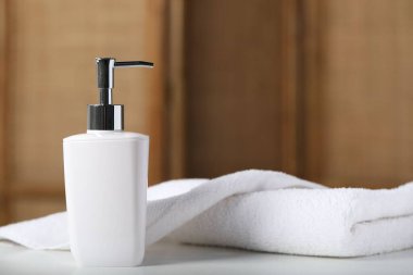 Şişede sıvı sabun ve beyaz masa içinde havlu.