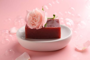Sabun barı ve pembe arka planda güzel bir gül, yakın plan.