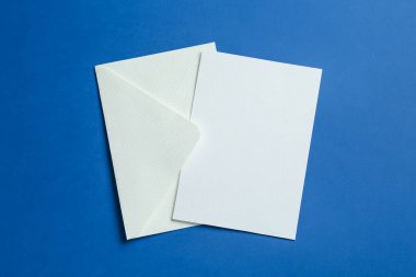 Mavi arka planda boş davetiye ve zarf, üst manzara. Tasarım için boşluk