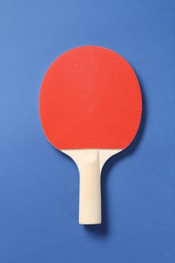 Mavi arka planda bir ping pong raketi, üst görünümde.