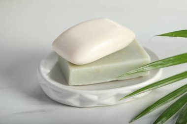 Beyaz mermer masada sabun çubukları ve palmiye yaprağı, yakın plan.