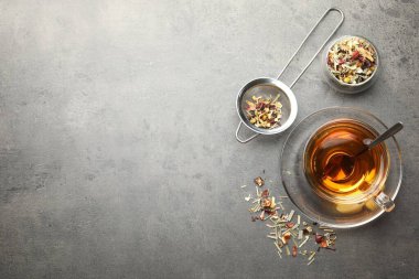 Aromatik bitki çayı ve kuru yapraklar gri masada, düz yerde. Metin için boşluk