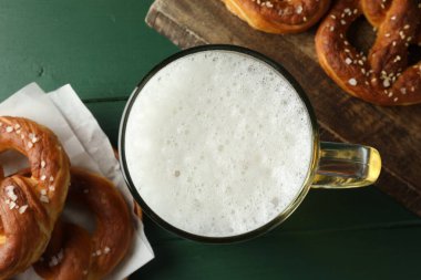 Lezzetli krakerler ve yeşil ahşap masada bir bardak bira.