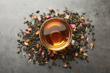 Aromatik bitki çayı, kuru yapraklar ve gri masada çiçekler, düz uzanmış.